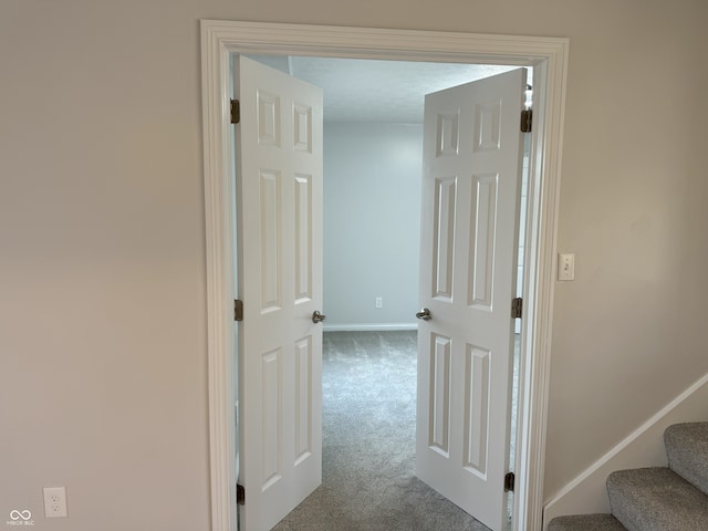 hall featuring carpet and a textured ceiling