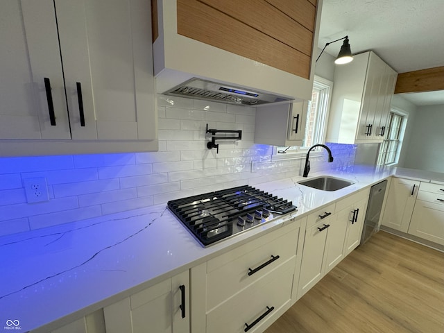 kitchen featuring light hardwood / wood-style floors, white cabinetry, sink, backsplash, and gas stovetop