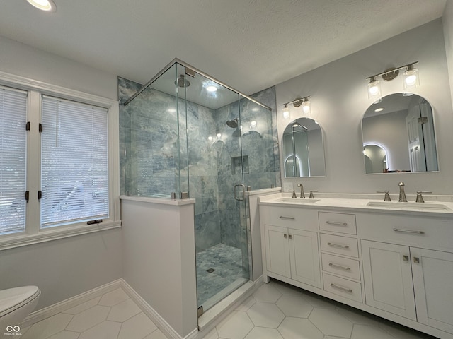 bathroom with vanity, a shower with shower door, tile patterned flooring, and a textured ceiling