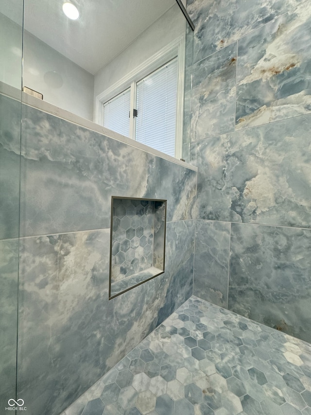 bathroom featuring tile walls and a tile shower