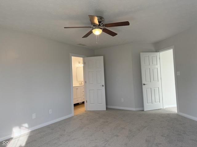 unfurnished bedroom with connected bathroom, light carpet, and ceiling fan