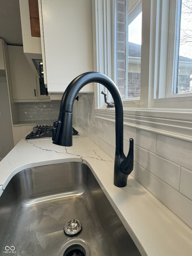 details with decorative backsplash, sink, and light stone counters