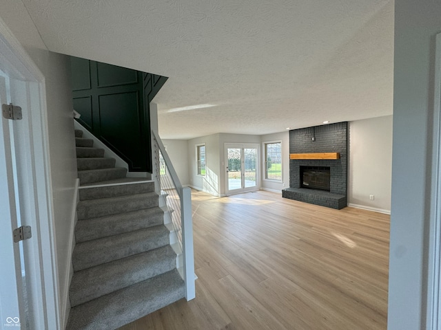 staircase featuring a textured ceiling, hardwood / wood-style flooring, and a brick fireplace