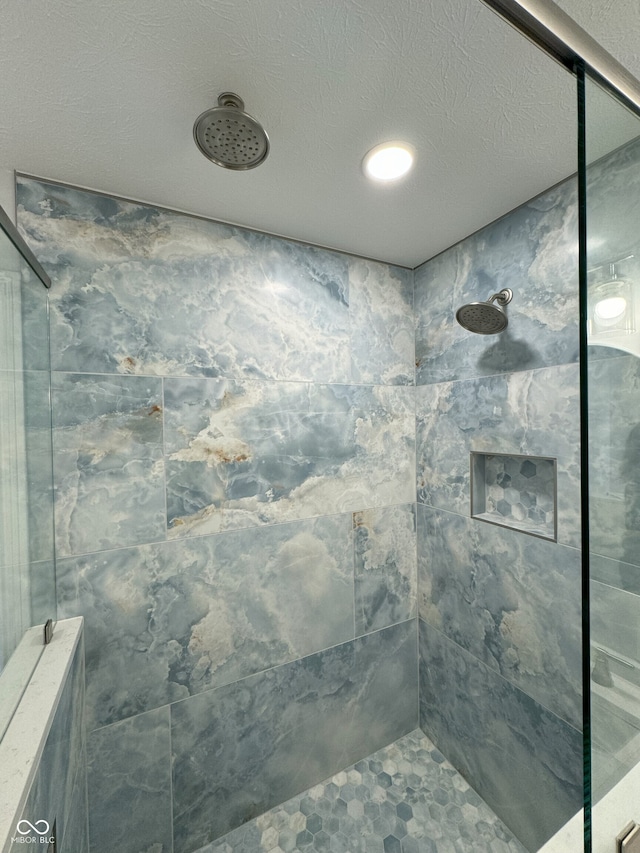 bathroom featuring a textured ceiling and a tile shower