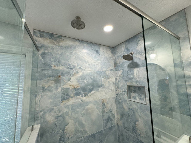 bathroom with a textured ceiling and a tile shower