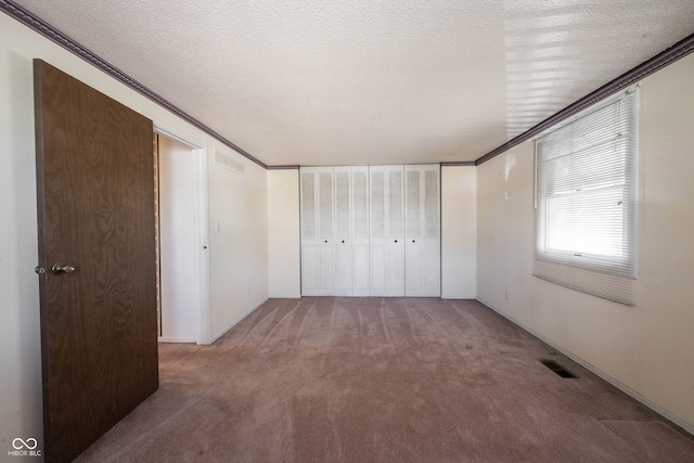 unfurnished bedroom featuring ornamental molding, carpet, and a textured ceiling