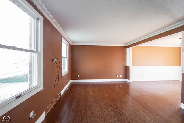 spare room with a wealth of natural light, dark wood-type flooring, and crown molding