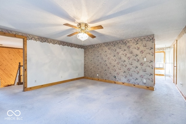 carpeted empty room with a textured ceiling, wooden walls, and ceiling fan