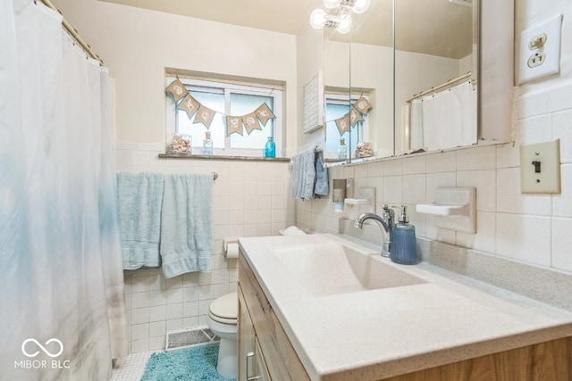 bathroom with toilet, vanity, tile patterned floors, and tile walls