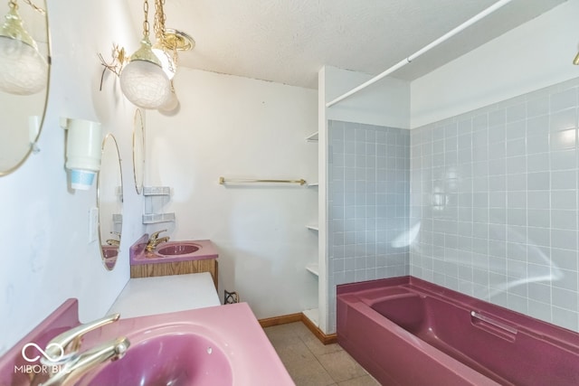 bathroom with tile patterned flooring, vanity, a textured ceiling, and tiled shower / bath