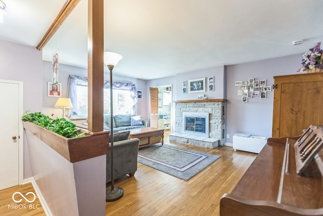 living room with a stone fireplace and light hardwood / wood-style flooring