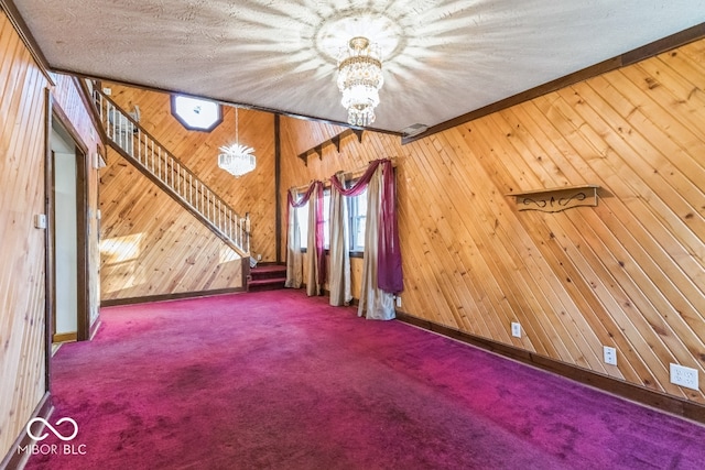 unfurnished living room featuring carpet floors, wood walls, crown molding, and an inviting chandelier