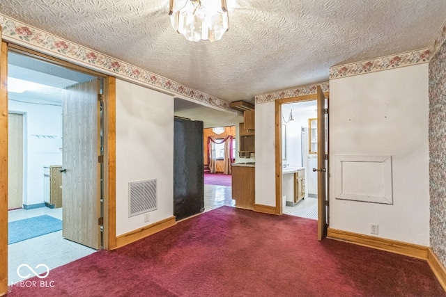 spare room featuring carpet and a textured ceiling