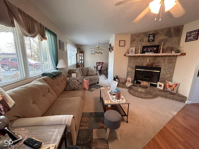 living room featuring a stone fireplace, hardwood / wood-style flooring, and ceiling fan