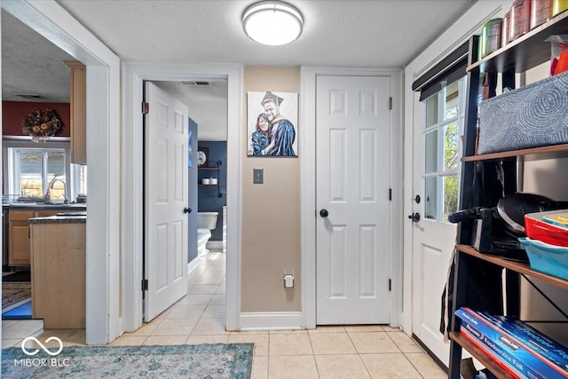 interior space with light tile patterned floors, a textured ceiling, and sink