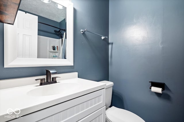 bathroom with vanity, toilet, and a textured ceiling