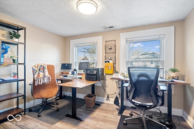 office with a textured ceiling and light wood-type flooring