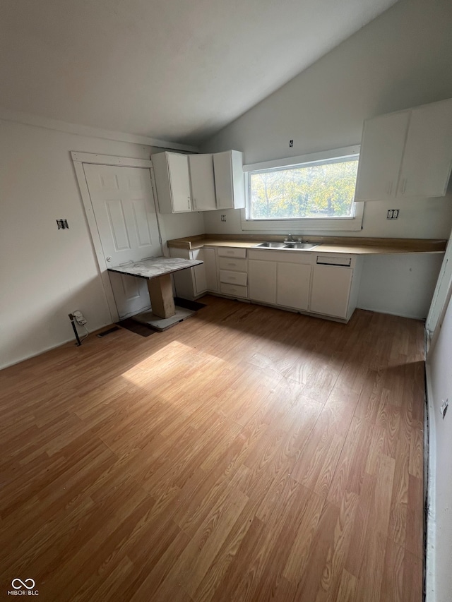 kitchen with white cabinets, light hardwood / wood-style floors, lofted ceiling, and sink