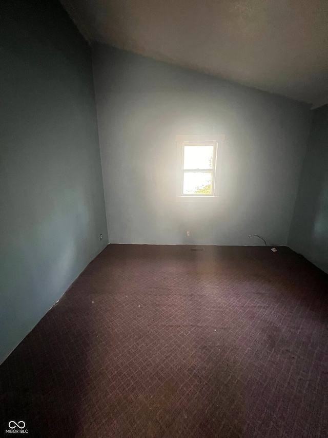 carpeted empty room with lofted ceiling