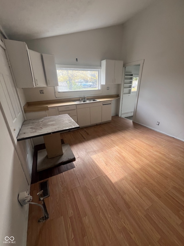 kitchen featuring white cabinetry, light hardwood / wood-style flooring, lofted ceiling, and sink