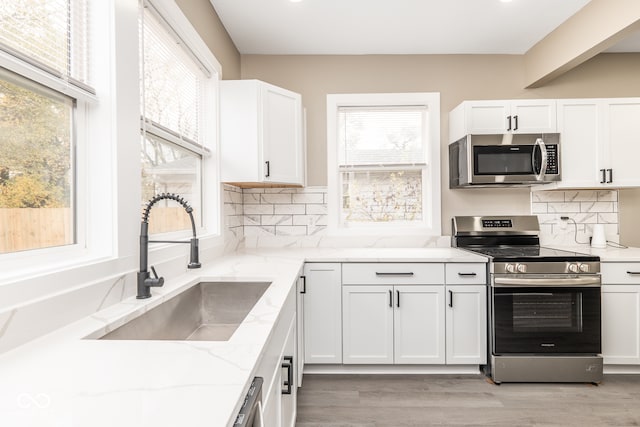 kitchen featuring a wealth of natural light, appliances with stainless steel finishes, sink, and light hardwood / wood-style floors