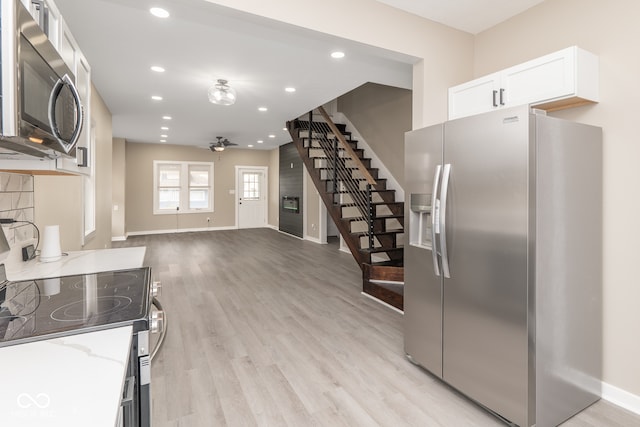 kitchen with light stone counters, stainless steel appliances, light wood-type flooring, white cabinetry, and ceiling fan