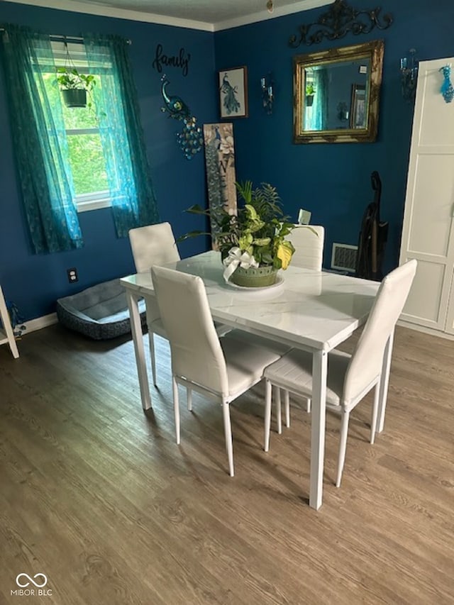 dining room with ornamental molding and hardwood / wood-style flooring