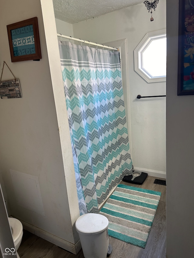 bathroom featuring walk in shower, wood-type flooring, and a textured ceiling