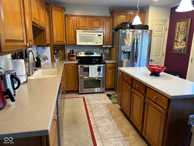 kitchen featuring appliances with stainless steel finishes, a textured ceiling, light tile patterned floors, hanging light fixtures, and sink