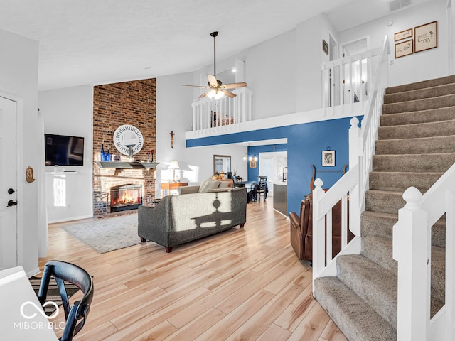 living room featuring a fireplace, ceiling fan, wood-type flooring, and high vaulted ceiling