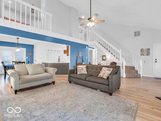 living room with hardwood / wood-style floors, ceiling fan, and high vaulted ceiling