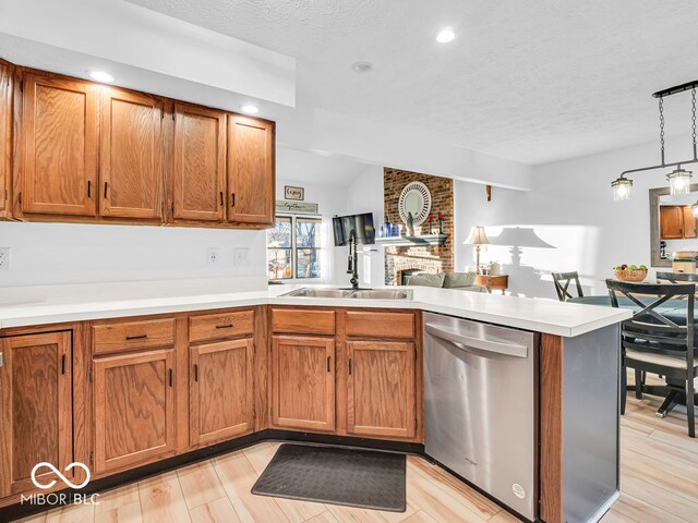 kitchen with sink, kitchen peninsula, light wood-type flooring, stainless steel dishwasher, and pendant lighting