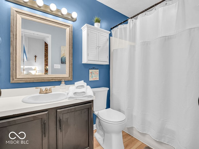 bathroom featuring hardwood / wood-style floors, a textured ceiling, toilet, and vanity