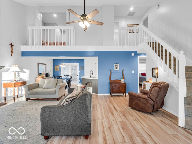 living room with high vaulted ceiling, light hardwood / wood-style floors, ceiling fan, and sink