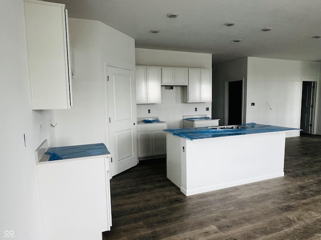 kitchen with a center island, dark hardwood / wood-style floors, and white cabinetry