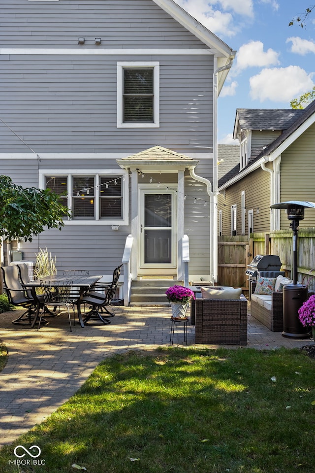 rear view of property featuring outdoor lounge area, a patio area, and a lawn