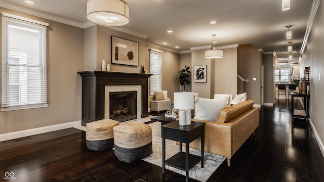 living room featuring dark hardwood / wood-style flooring, ornamental molding, and a tiled fireplace