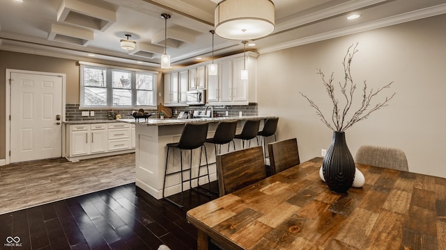 kitchen with white cabinetry, light stone countertops, kitchen peninsula, pendant lighting, and ornamental molding