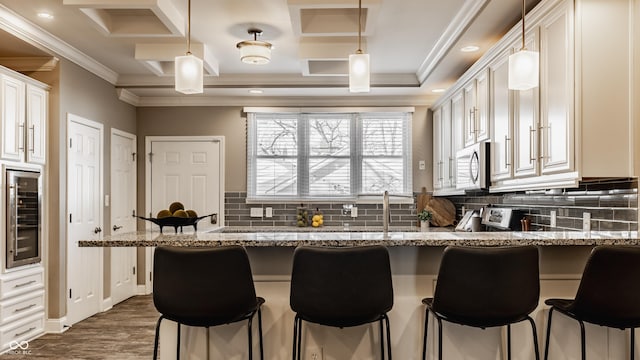 kitchen with decorative light fixtures, a kitchen bar, light stone countertops, and wine cooler