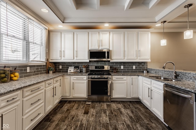 kitchen featuring appliances with stainless steel finishes, light stone counters, sink, pendant lighting, and white cabinetry