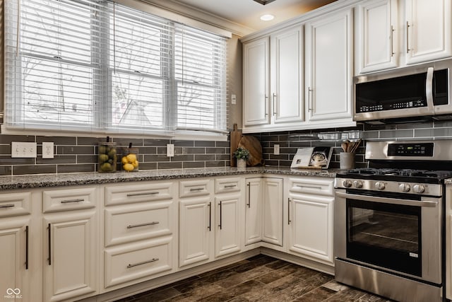 kitchen featuring light stone countertops, decorative backsplash, stainless steel appliances, and white cabinetry