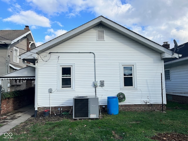 back of property featuring cooling unit and a lawn