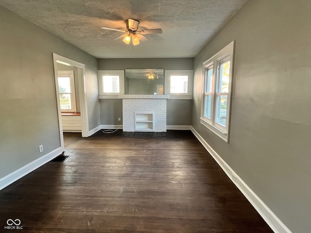 unfurnished living room with a textured ceiling, dark wood-type flooring, a healthy amount of sunlight, and ceiling fan