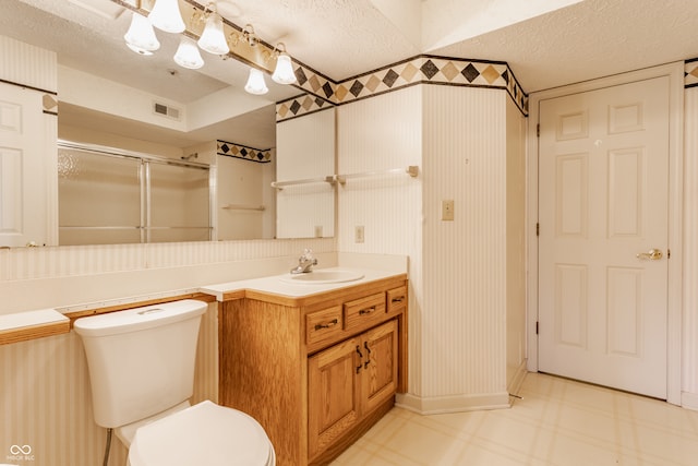 bathroom with vanity, a shower with door, a textured ceiling, and toilet