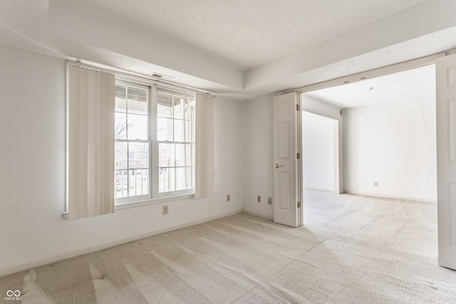 empty room featuring a textured ceiling and light colored carpet