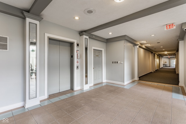 hall featuring ornate columns, elevator, a textured ceiling, and light tile patterned flooring