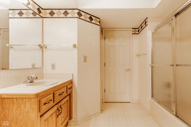 bathroom featuring vanity, bath / shower combo with glass door, and a textured ceiling