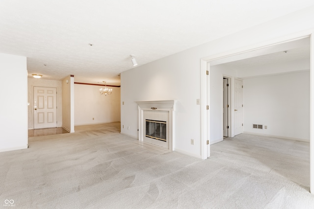 unfurnished living room featuring light colored carpet, a tile fireplace, and a chandelier