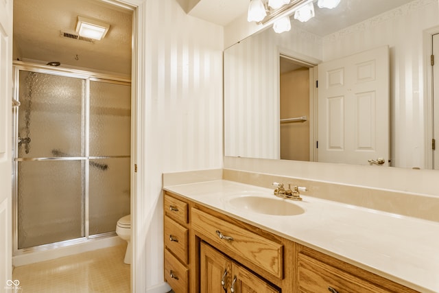 bathroom with a shower with shower door, vanity, toilet, and a textured ceiling