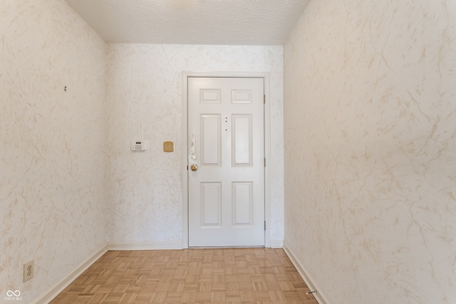 doorway to outside featuring a textured ceiling and light parquet floors